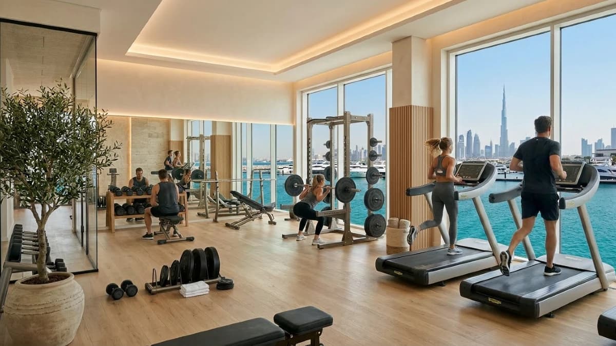 Spacious luxury living room with Nordic oak flooring, minimalist furnishings, and floor to ceiling windows framing the Dubai waterfront skyline.